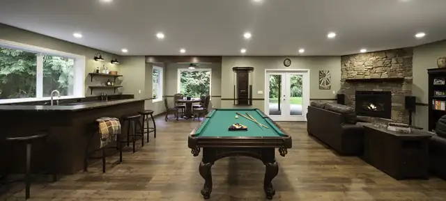 Entertainment-focused basement remodel in Marysville, WA with a wet bar, pool table and stone fireplace