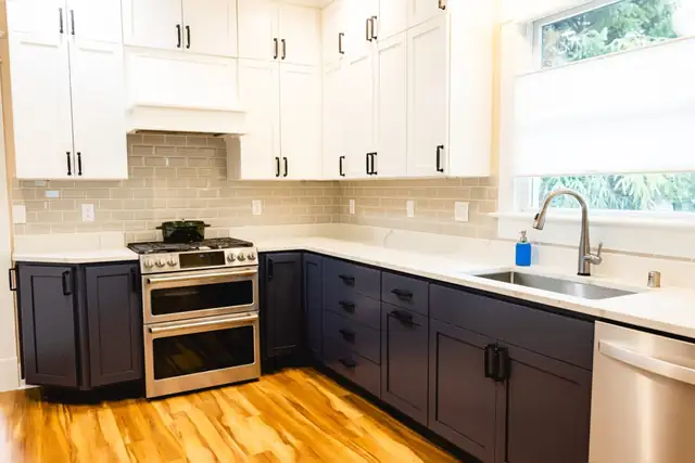 Kitchen remodel in Everett, WA with navy lower cabinets, white uppers, gas range and warm wood floor