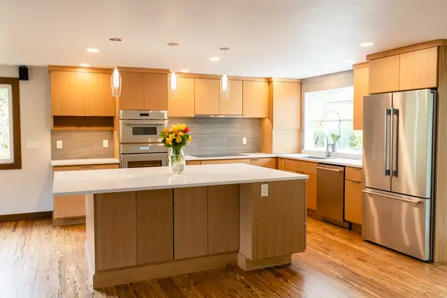 Light and airy Lynnwood, WA kitchen with natural wood cabinets, a white quartz island, pendant lights and stainless appliances
